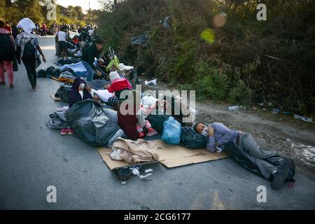 Lesvos, Griechenland. September 2020. Migranten und Flüchtlinge ruhen auf einer Straße nach einem großen Brand auf das Flüchtlings- und Migrantenlager Moria auf der nordöstlichen Ägäischen Insel Lesvos, Griechenland, am 9. September 2020. In den frühen Morgenstunden des Mittwochs brach in Griechenlands größtem Flüchtlings- und Migrantenlager Moria ein großes Feuer aus, berichtete die griechische nationale Nachrichtenagentur AMNA. Das Feuer hat sich auf das gesamte Empfangszentrum ausgebreitet. Quelle: Xinhua/Alamy Live News Stockfoto