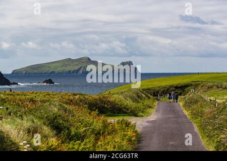 Touristen, die auf einer Landstraße zum Strand auf der Halbinsel Dingle gehen, im Hintergrund Great Blaskets Island Stockfoto