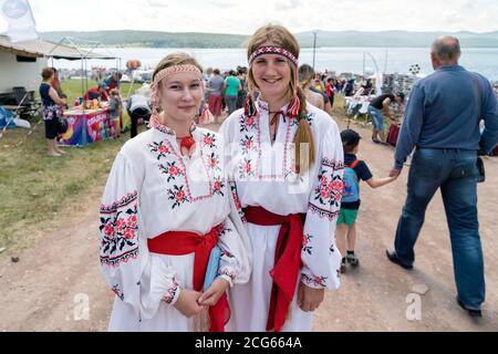 Mädchen in volkstümlichen ukrainischen Kostümen stehen auf einer Einkaufsstraße beim Karatag Musikfestival. Region Krasnojarsk. Russland. Stockfoto