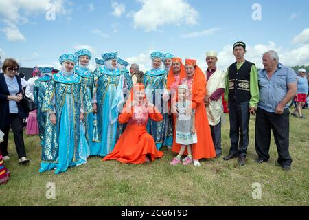 Festivalteilnehmer in russischen und tatarischen Volkstrachten stehen auf einer Lichtung beim Karatag Musikfestival. Region Krasnojarsk. Russland. Stockfoto