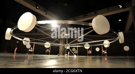 Eine allgemeine Ansicht der Jon Fawcett-Installation "EIR", sechs Kabinen, die von Psychikern bemannt sind, die Mitglieder der Öffentlichkeit für eine mögliche Rekrutierung bei einer geheimen Organisation abschirmten, und Whum, ein 7 Meter breites, langsam drehendes Rad mit neun zylindrischen Gefäßen, die nicht offengelegte Materialien auf seinem Rand enthalten, umgeben von zehn weiteren, Das ist Teil der Undercurrent: Young People's Ausstellung in der Tate Modern, London. Stockfoto