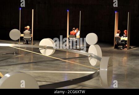 Eine allgemeine Ansicht der Jon Fawcett-Installation "EIR", sechs Kabinen, die von Psychikern bemannt sind, die Mitglieder der Öffentlichkeit für eine mögliche Rekrutierung bei einer geheimen Organisation abschirmten, und Whum, ein 7 Meter breites, langsam drehendes Rad mit neun zylindrischen Gefäßen, die nicht offengelegte Materialien auf seinem Rand enthalten, umgeben von zehn weiteren, Das ist Teil der Undercurrent: Young People's Ausstellung in der Tate Modern, London. Stockfoto