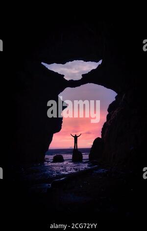 Blick aus einer Höhle eines Mannes, der auf einem Felsen im Meer steht, Island Stockfoto