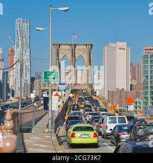 New York, New York State, Vereinigte Staaten von Amerika. Starker Morgenverkehr, der die Brooklyn Bridge von der Brooklyn-Seite aus erreicht. Manhattan im Hintergrund. Stockfoto