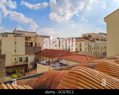 Blick vom roten Ziegeldach über geschlossenen gemütlichen Hof umgeben von Schulgebäude und alten traditionellen Häusern in sandigen Farben mit Terrassen und Balkonen. Stockfoto