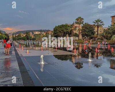 Beleuchtete Brunnen im Herzen der Stadt Nizza, Promenade du Paillon. Kinder spielen an den Wasserquellen am Abend, in der Dämmerung. Frankreich. Stockfoto