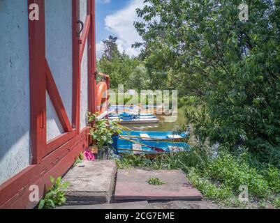 Blick über alte Bootstation mit Pontonschwimmer Kai mit Soviet Times Tretboote und Tretboote im Park See an einem sonnigen Tag. Stockfoto