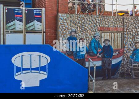 Vor dem Mo Museum, Sheringham, Norfolk - ein Wandbild einer alten Rettungsbootcrew, Logo und Poster Stockfoto