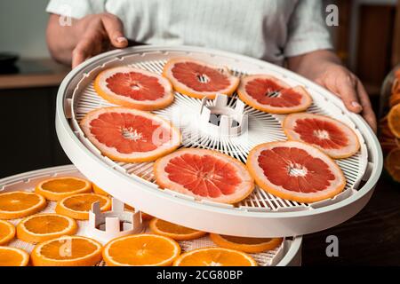 Nahaufnahme einer unkenntlichen Frau, die Kunststoff-Entfeuchtertabletts mit Fresh zusammengebaut hat Obst in der Küche Stockfoto