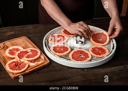 Nahaufnahme einer nicht erkennbaren Frau, die Grapefruitscheiben auf die Entfeuchterschale legt Während der Zubereitung von Snacks Stockfoto