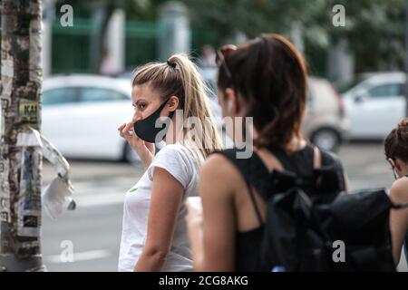 BELGRAD, SERBIEN - 28. AUGUST 2020: Zwei junge Frauen tragen eine Atemmaske, eine hält ihr Telefon, um während eines Telefonanrufs mit ihrem Smart zu diskutieren Stockfoto