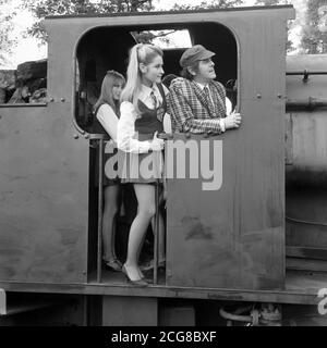 Portland Mason, Schauspielerin Tochter von James Mason, und George Cole (Flash Harry, die Schule "Buchmacher") auf der Fußplatte während Drehort für "The Great St. Trinian's Train Robbery" im Longmoor Army Camp, Hampshire. Die Militäreisenbahn des Lagers wurde für Szenen aus dem Film verwendet, in dem Portland als Georgina in St. Trinian ihr Leinwanddebüt gibt. Stockfoto