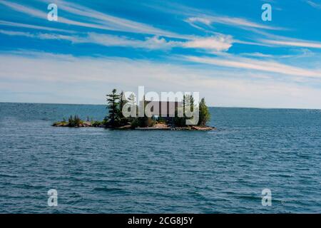 Gebäude auf einer kleinen Insel in einem großen See versteckt Große Bäume und Sträucher Stockfoto