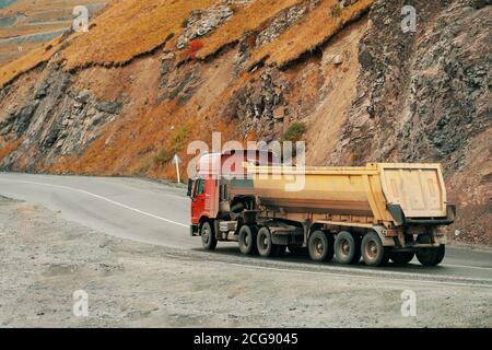 LKW, der Schüttgüter transportiert, bewegt sich auf einer Straße auf dem Bergautobahn Stockfoto