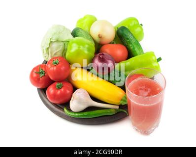 Ein Glas frischen Gemüsesaft und eine große Auswahl an frischem Gemüse auf einem runden Tablett auf weißem Hintergrund. Stockfoto
