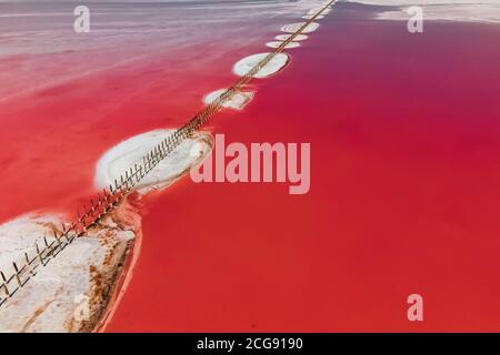 Top Luftaufnahme des unglaublichen rechts rosa See. Salar mit Holzbalken und Salzinseln in der Mitte. Stockfoto