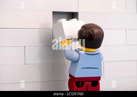 Tambow, Russische Föderation - 07. Juni 2020 Lego man Minifigur mit grauem Ziegel, der eine Wand fertig stellt Stockfoto