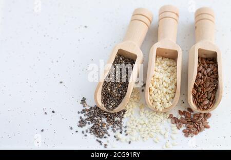 Gesundes Saatgut Konzept. Holzlöffel mit weißen Sesam-, Flachs- und Chiasamen Stockfoto