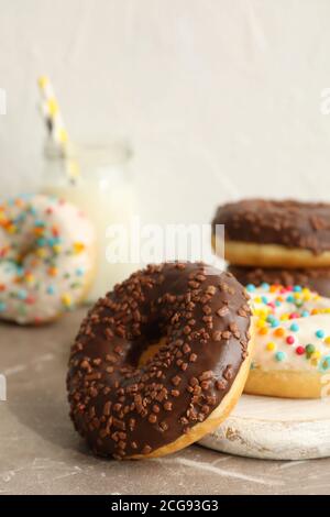 Glas Milch und leckere Donuts auf grauem Tisch Stockfoto