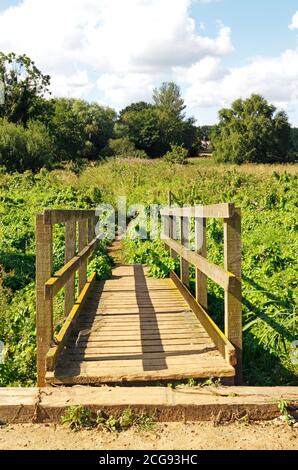 Eine hölzerne Fußgängerbrücke auf dem Canal Walk zum ausgedient North Walsham und Dilham Canal in North Walsham, Norfolk, England, Vereinigtes Königreich. Stockfoto