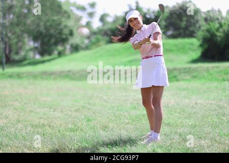 Frau Golfer mit Golfschläger in der Hand und fliegende Kugel Nach dem Schlagen Stockfoto