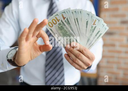 Geschäftsmann hat hundert Dollar Scheine in der Hand mit Sekundenhand zeigt die Geste ok. Stockfoto