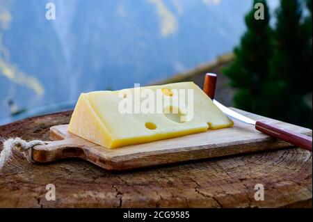 Käsesammlung, französischer emmental de savoie Käse mit runden Löchern, serviert im Freien in der Savoyer Region, mit Berggipfeln im Sommer auf dem Backgrou Stockfoto