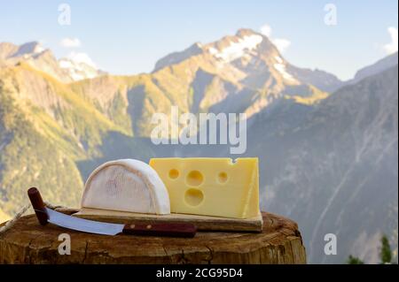 Käsesammlung, französisches Reblochon und emmental de savoie Gratin serviert im Freien mit Berggipfeln im Sommer im Hintergrund Stockfoto