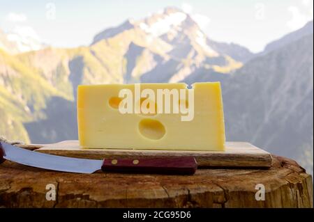 Käsesammlung, französischer emmental de savoie Käse mit runden Löchern, serviert im Freien in der Savoyer Region, mit Berggipfeln im Sommer auf dem Backgrou Stockfoto
