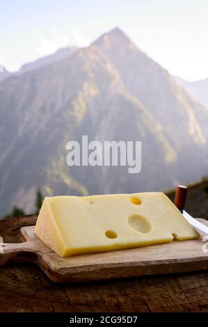 Käsesammlung, französischer emmental de savoie Käse mit runden Löchern, serviert im Freien in der Savoyer Region, mit Berggipfeln im Sommer auf dem Backgrou Stockfoto