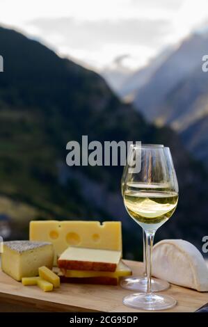 Schmackhafter Käse und Wein aus Savoyen in Frankreich, beaufort, abondance, emmental, Tomme und Reblochon de savoie Käse und ein Glas Weißwein serviert Stockfoto