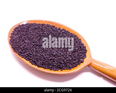 Schwarzer Kreuzkümmel, Nigella Sativa in Holzlöffel auf weißem Hintergrund. Konzept der Kräutermedizin Stockfoto