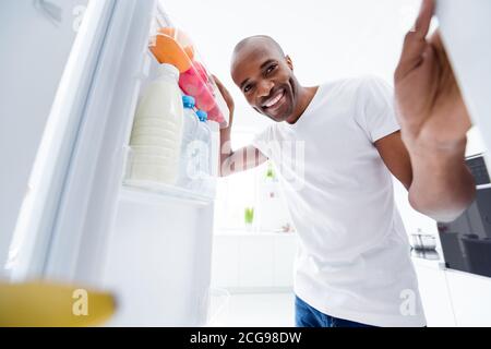 Portrait von seinem er schön attraktiv fröhlich fröhlich hungrig gesund Mann, der im Kühlschrank sah, frisch, lecker, lecker, vitaminvegs Essen In hellweißem Innenraum Stockfoto