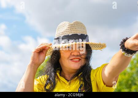 Eine Asiatin mittleren Alters, Mitte 50, mit Strohhut. Stockfoto