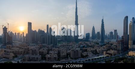 11/2020 - Dubai, Vereinigte Arabische Emirate: Ikonisches Panorama bei Sonnenuntergang des Burj Khalifa und der Dubai Skyline, wenn die Sonne mit und anderen Wolkenkratzern in der Mitte untergeht Stockfoto