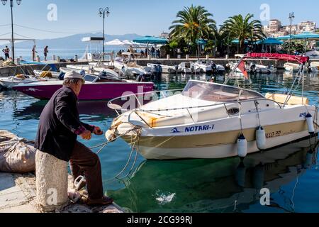 Ein Einheimischer, der im Hafen, Saranda, Albanien angeln kann. Stockfoto