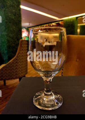 Weinglas auf schwarzem Tisch mit verschwommener Inneneinrichtung eines Restaurants im Hintergrund. Stockfoto