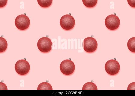Urlaub samless Muster. Rote weihnachtsglaskugeln mit Glitzern auf pastellrosa Hintergrund. Weihnachtskonzept. Draufsicht, flach liegend. Stockfoto