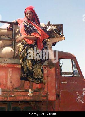 1993 - Gerade auf Schuß eines somalischen Frau auf der rechten Seite des dump Rack Klammern auf einem Isuzu Dump Truck. Sie beobachtet die Männer laden Sie die Säcke Weizen gespendet, die von den Menschen in Australien (nicht abgebildet). Diese Mission ist in der direkten Unterstützung der Operation Restore Hope. Stockfoto