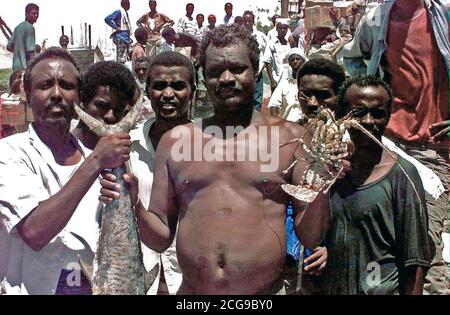 1993 - Zwei somalische Männer stehen vor der Kamera und halten einige der Seafood zu Beachside Markt in Mogadischu zur Verfügung. Vier andere Somalische Männer stand direkt hinter den beiden Ersten und vor der Kamera befinden. Stockfoto