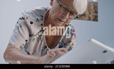 Alte grauhaarige Frau mit Augenmuschel mit dem tabet. Low-Angle-Aufnahme. Hochwertige Fotos Stockfoto