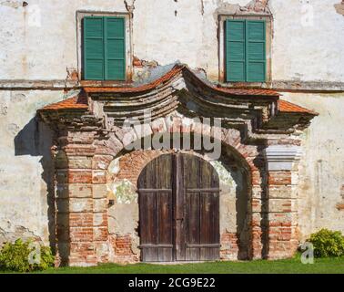 Retro Holztür in der Burg vor dem Wiederaufbau. Zwei Fenster mit grünen Fensterläden aus Holz. Stockfoto