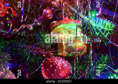 Weihnachtsbaum Urlaub Hintergrund mit Glas Spielzeug, die Girlande, Bälle, Lichter. Bunte Dekoration Nahaufnahme in dunklen Schlüssel. Stockfoto