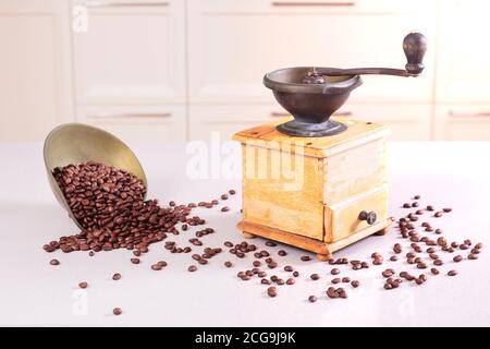 Alte antike Kaffeemühle und eine Schüssel mit verschütteten Bohnen Stockfoto