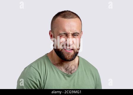 Verspielter bärtiger Mann im lässigen grünen T-Shirt winkt an der Kamera flirtet Sie über weißen Hintergrund. Stockfoto