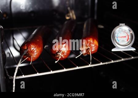 Kochen gekochte geräucherte Wurst zu Hause. Drei Brote Wurst im Ofen, selektive Fokus. Stockfoto