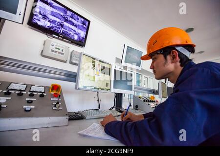 Titanmetallurgie-Anlage. Der junge Arbeiter steuert die Verarbeitung von schmelzendem Titan mit Vakuum-Lichtbogen furnace.computers und Lampenanzeigen. Stockfoto