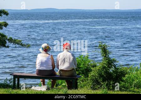 Eine alte Frau und ein Mann sitzen auf einer Bank Am Meer und Blick in die Ferne Stockfoto