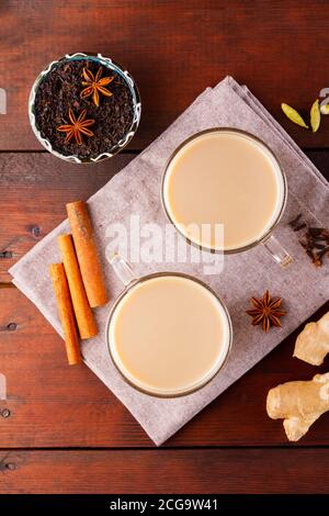 Masala Chai Tee auf Leinenserviette. Traditionelles indisches Getränk - Masala-Tee mit Gewürzen auf Holzgrund. Draufsicht Stockfoto