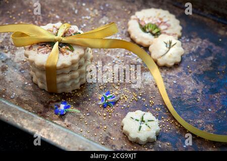 Kleiner Stapel Shortbread-Kekse mit Fliege, essbaren Blumen und Goldzucker, Hochwinkelansicht Stockfoto